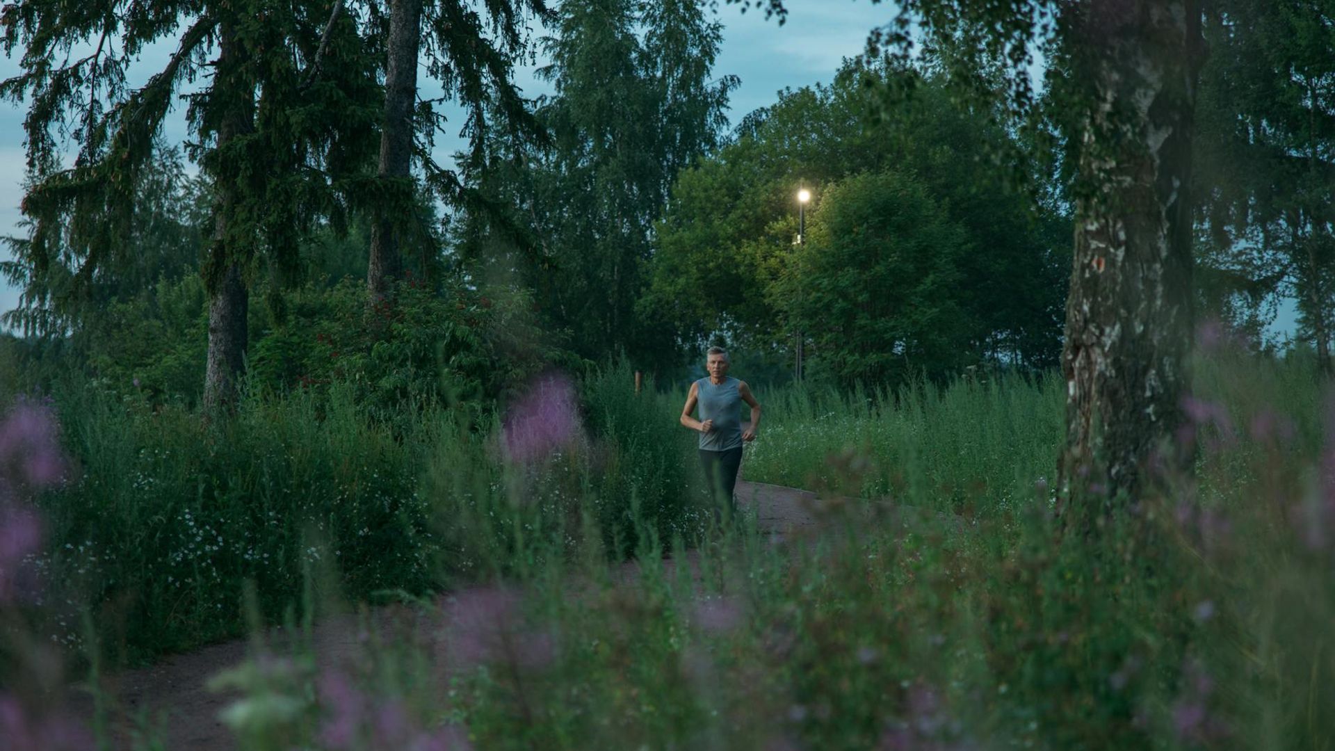 Person running in a lush green park during sunrise